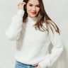 Front view of model wearing the Get Cozy Sweater that has ivory knit fabric with a faux-hair texture, a round neckline, dropped shoulders, and long balloon sleeves with cuffs.