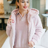 Front view of model wearing the Let It Snow Faux Fur Jacket in Pink that has light pink faux fur, a front zipper, front pockets, an elastic waist, a hood, and long sleeves with elastic wrists.