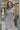 Front view of model wearing the Call Me Later Sweater Dress that has grey knit fabric, a mini length hem, a loose turtleneck, and a sleeveless body.