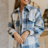 Front view of model wearing the Mountain Weekend Shacket in Blue that has blue, grey, black and white plaid, a satin lining, a button-up front, a collar, two chest pockets, and long sleeves.