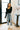 Front view of model wearing the Amelia High-Waisted Jeans that have structured medium-wash denim with distressed knees, straight legs with frayed ankles, a high-rise waist with a button + zipper closure, and front &amp; back pockets