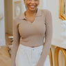 Front view of model wearing the Downtown Days Top in Khaki that has khaki ribbed fabric, a cropped waist, a v neckline with a collar, and long sleeves.