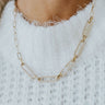 Close up view of model wearing the Day Dreamer Pearl Necklace which features gold chain links, small and large squared shaped with pearls.