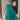 Full body view of model wearing the No More Wishing Dress which features kelly green fabric with a lining, a tiered midi-length skirt, a ruched neckline, adjustable thick straps, and a smocked back.