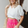 Front view of model wearing the Let's Get Away Shorts that have hot pink acid wash fabric, a frayed hem, two side pockets, two back pockets, and an elastic high-rise waistband