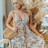 Front view of model wearing the What A Feeling Dress that has a grey, taupe, and cream swirl print, a deep v-neck and back, elastic at the waist, thick straps, and side ruffle details