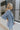 Side view of model wearing the Once Upon A Time Blazer which features light blue fabric, two front pockets, a collared neckline, and 3/4 sleeves with ruched details.
