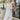 Front view of model wearing the Picture Perfect Midi Dress in White that has sheer white fabric with a checkered pattern, a white lining, a tiered midi-length body, side pockets, and tiered cap sleeves.