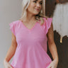 Front view of model wearing the Must Be Fate Top that has pink knit fabric, tiered cap sleeves, a v-neckline, and raw hems.
