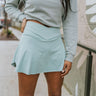 Front view of model wearing the Step It Up Skort in Sage that features sage fabric, shorts lining, a v overlap waistline, slits on each side, and a mini-length hem.