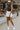 Full body front view of model wearing the Step It Up Skort in White that has white fabric, shorts lining, a v overlap waistline, slits on each side, and a mini-length hem