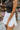 Close front view of model wearing the Step It Up Skort in White that has white fabric, shorts lining, a v overlap waistline, slits on each side, and a mini-length hem
