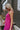 Side view of model wearing the On The West Coast Top that has fuchsia fabric with a textured line design, a peplum hem, a square neckline, and thick straps.