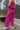 Side view of model wearing the On The West Coast Pants that feature fuchsia fabric with a textured line design, two front pockets, an elastic waistband, and flared legs.