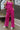 Front view of model wearing the On The West Coast Pants that feature fuchsia fabric with a textured line design, two front pockets, an elastic waistband, and flared legs.