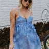 Front view of model wearing the Take Me To The Hamptons Romper that has blue and white vertical stripes, white shorts lining, adjustable spaghetti straps, a v-neck, side pockets, and an elastic back