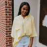 Front view of model wearing the Bring Back Summer Top in Yellow which features yellow gauze fabric, an oversized fit, two front chest pockets, a v cutout with a round neckline, dropped shoulders, and short sleeves.