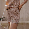 front view of model wearing The Corsica Knit Checkered Shorts features light brown and off white textured knit fabric, skinny checkered pattern, elastic waistband and two side pockets.