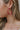 Close up view of model wearing the Hot Summer Earring which features hot pink large hoop shaped earring with roping details.