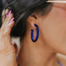Close up view of model wearing the Moody Blues Earrings which features cobalt blue medium hoop shaped earring with roping details.