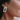 Close up view of model wearing the Naples Village Earring in Pink which features pink round marble bead linked to iridescent rectangle shaped hoop.