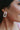 Close up view of model wearing the Naples Village Earring in Pink which features pink round marble bead linked to iridescent rectangle shaped hoop.