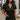 Front view of model wearing the Dakota Denim Romper in Black that has black denim fabric, front pockets, a hidden front zipper, a collared neckline, a monochromatic belt at the waistline, and short sleeves