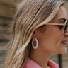 Side view of model wearing the Go Around Hoop Earring which features white mini hoop shaped earring with roping details.