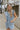 Front view of model wearing the Are You Ready Romper that has washed lightweight denim fabric, front pockets, two back pockets, a hidden front snap closure, a collar, short sleeves, and  frayed hems.