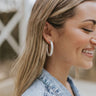 Close up view of model wearing the What A Classic Hoop Earrings which features brushed silver medium open hoop shaped.