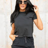 Front view of model wearing the Easy Going Top in Black which features black cotton fabric, a cropped waist, a round neckline, and short sleeves. Top is front tucked.