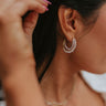 Close up view of model wearing the Day Dreaming Hoops which features mini gold shaped triple hoops with clear stones and pearls.