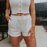 Front view of model wearing the In My Element Shorts which features off white knit fabric with a ribbed pattern, two side pockets, and an elastic waistband with drawstring ties.