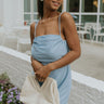 Front view of model wearing the Day to Day Dress which features light blue textured fabric, light blue lining, a square neckline, braided straps with adjustable ties, an open back and an elastic waistband.
