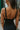 Back view of model wearing the Find Yourself Jumpsuit which features black stretchy fabric, a low round neckline, thick adjustable straps, and a sleeveless design.