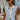 Front view of model wearing the Good For You Denim Vest that has light wash denim fabric, a cropped waist, silver buttons, a collar, front chest pockets, and distressed detailing, light brown stitching.