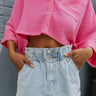 Front view of model wearing the Heat Wave Shorts that have light wash denim fabric, a high-rise elastic waistband with belt loops, two front pockets, two back pockets, and a raw hem.