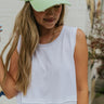 Front view of model wearing the City Life Cropped Tank In White that has soft-white fabric, a round neckline, thick straps, raw hem details, and a short-wide fit.