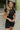 Front view of model wearing the Bring It On Romper that has black stretchy fabric, a romper body, a monochromatic front zipper, a round neckline, and short sleeves.