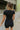 Back view of model wearing the Bring It On Romper that has black stretchy fabric, a romper body, a monochromatic front zipper, a round neckline, and short sleeves.