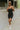 Full front view of model wearing the Call It Even Romper that features black stretch fabric, a romper body, a round neckline, bra padding, and adjustable spaghetti straps.