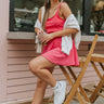 Front view of model sitting in chair while wearing the Movement Mini Dress in Pink, with sweater over arms.