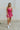 Full body front view of model wearing the Movement Mini Dress in Pink that has a ribbed upper body, ribbed shorts, a lightweight skirt with a flare out hem, a smocked waist, a scooped neck and thick straps,