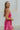 Side view of model wearing the Movement Mini Dress in Pink that has a ribbed upper body, ribbed shorts, a lightweight skirt with a flare out hem, a smocked waist, a scooped neck and thick straps,