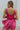 Back view of model wearing the Movement Mini Dress in Pink that has a ribbed upper body, ribbed shorts, a lightweight skirt with a flare out hem, a smocked waist, a scooped neck and thick straps,