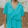 Front view of model wearing the Pool Days Ahead Shorts which features teal textured fabric with a monochromatic checkered print, two front pockets, two back pockets, an elastic waistband and teal lining.