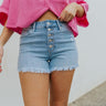 Front view of model wearing the Just USA Denim: Dream On Shorts in Light Wash which features light wash denim fabric, high waisted with belt loops, front multiple buttons closure, two front pockets, two back pockets, distressed detailing and fray hem.