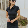 Front view of model wearing the Didn't You Know Dress which features black fabric, a mini-length hem, a monochromatic quarter button up, a collared neckline, and short sleeves.