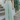 Front view of model wearing the On The Lookout Pants which features light sage fabric, a hidden front zipper with a tortoise button closure, an elastic back waistband, two front pockets and flared legs.