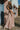 Full body front view of model wearing the Melrose Avenue Pleated Pants that have blush-colored pleated fabric, blush lining, an elastic waistband, and wide legs